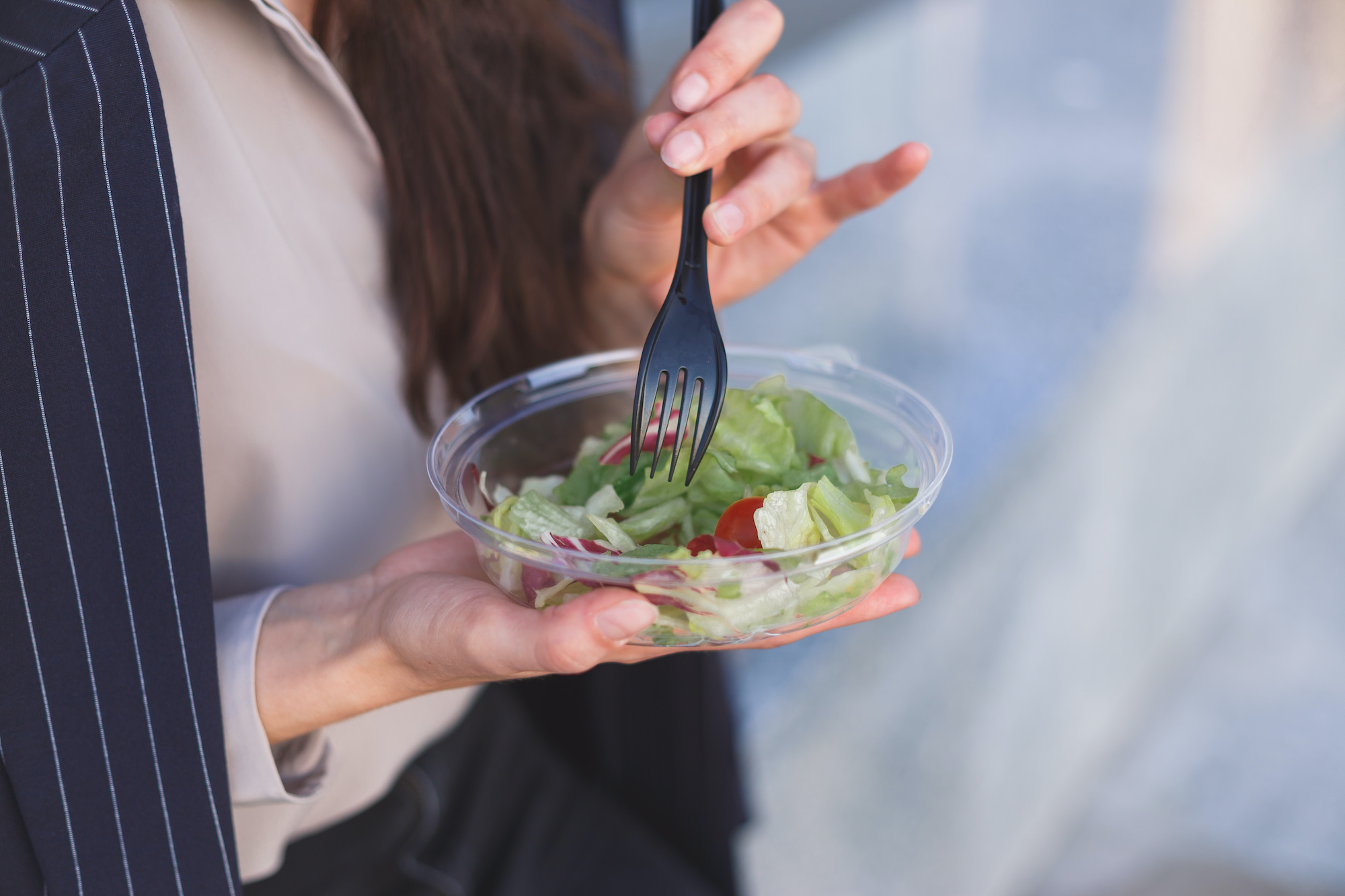 Office worker eats salad sitting outdoor.